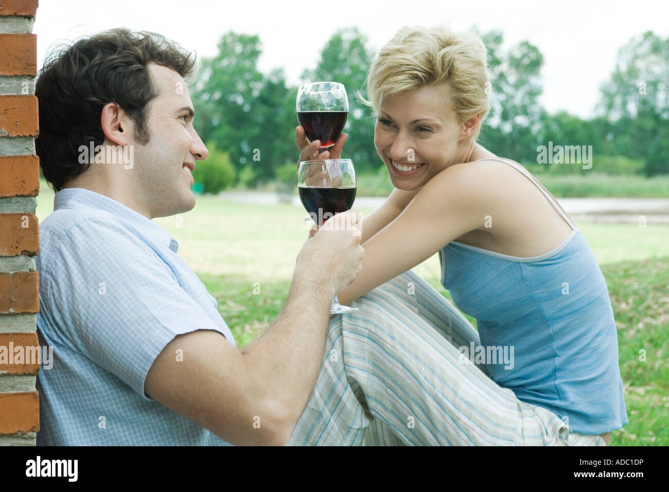 Paar im Freien sitzen, toasten mit Gläser Rotwein Stockfoto