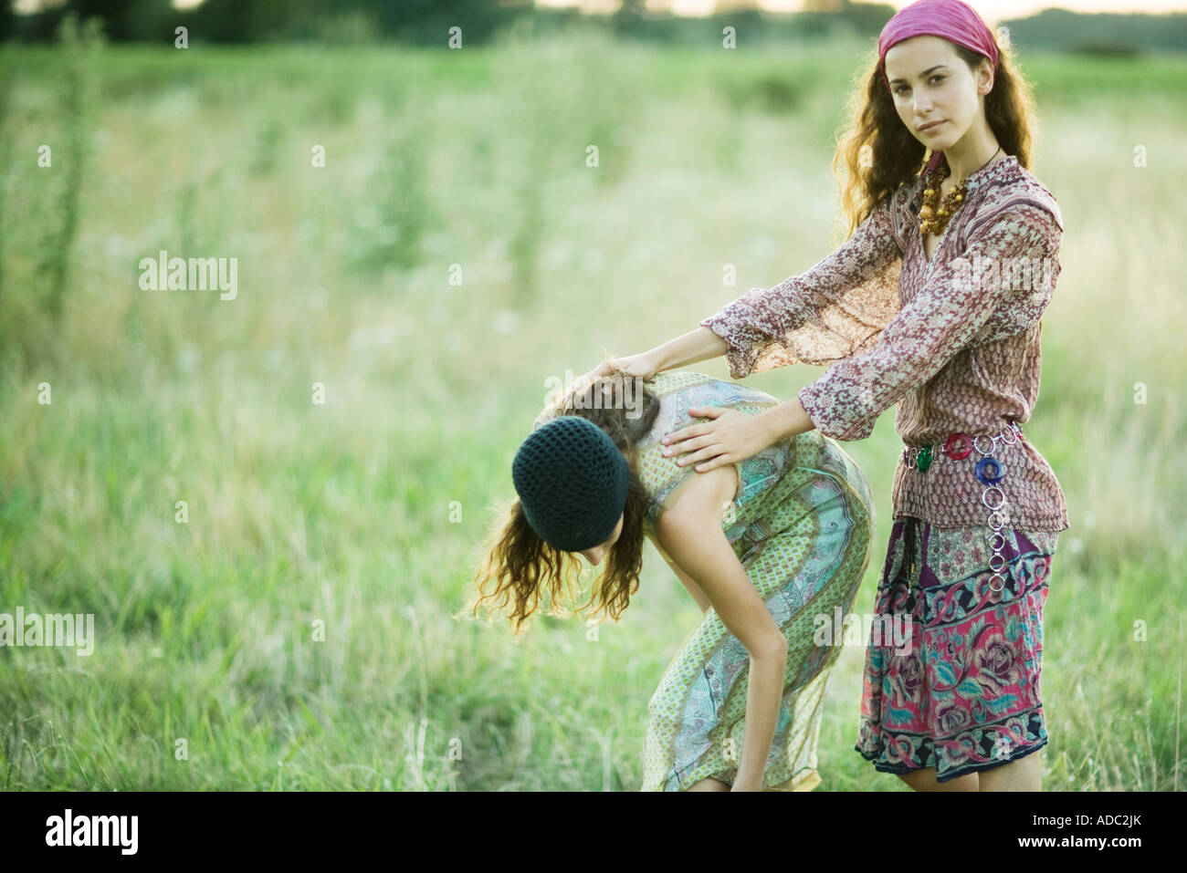 Junge Frauen im Feld, ein bücken während der andere hält den Rücken Stockfoto