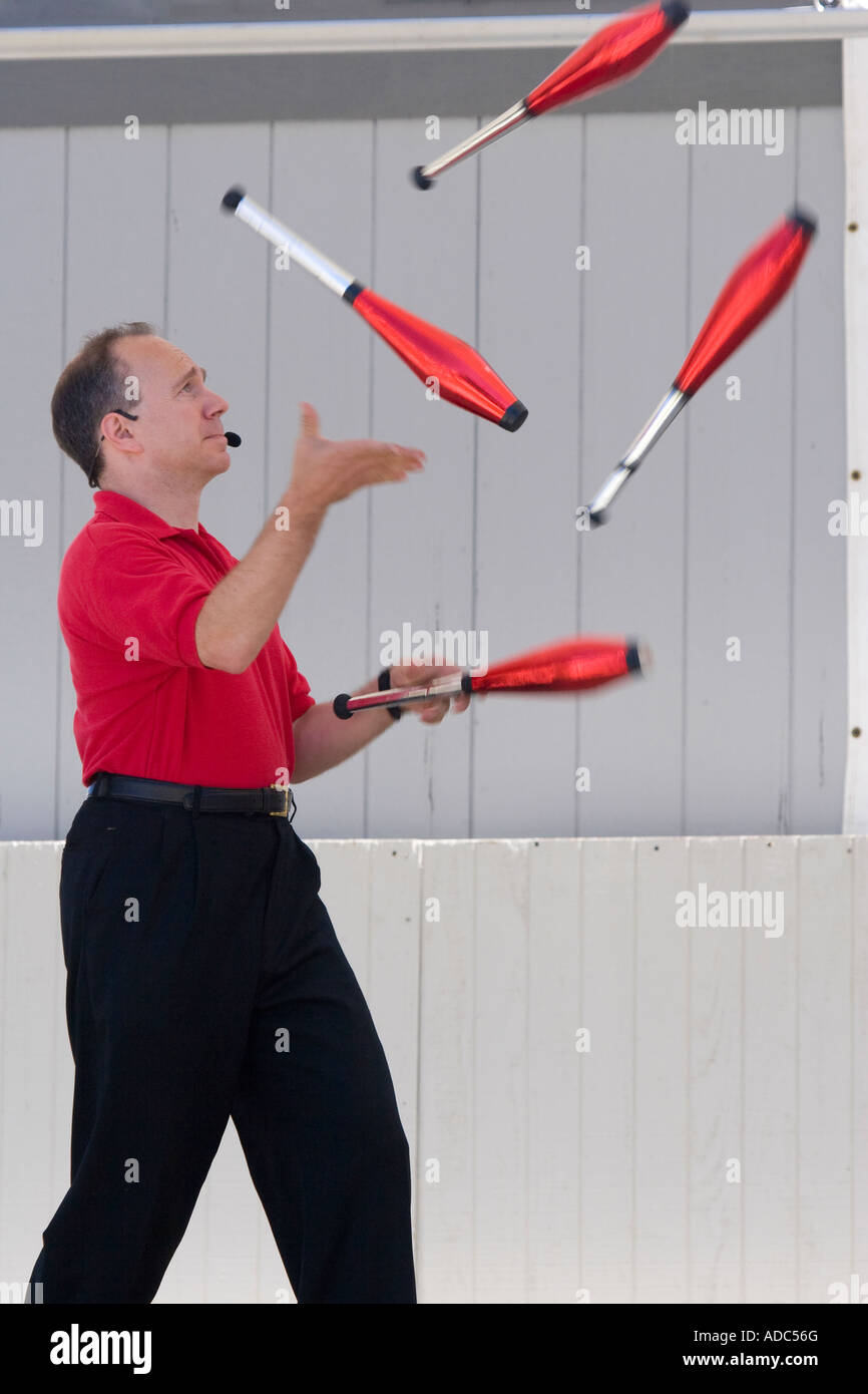 Männliche Jongleur mit Pins in einem roten und schwarzen Outfit passend seine roten Pins Jonglage jonglieren Stockfoto