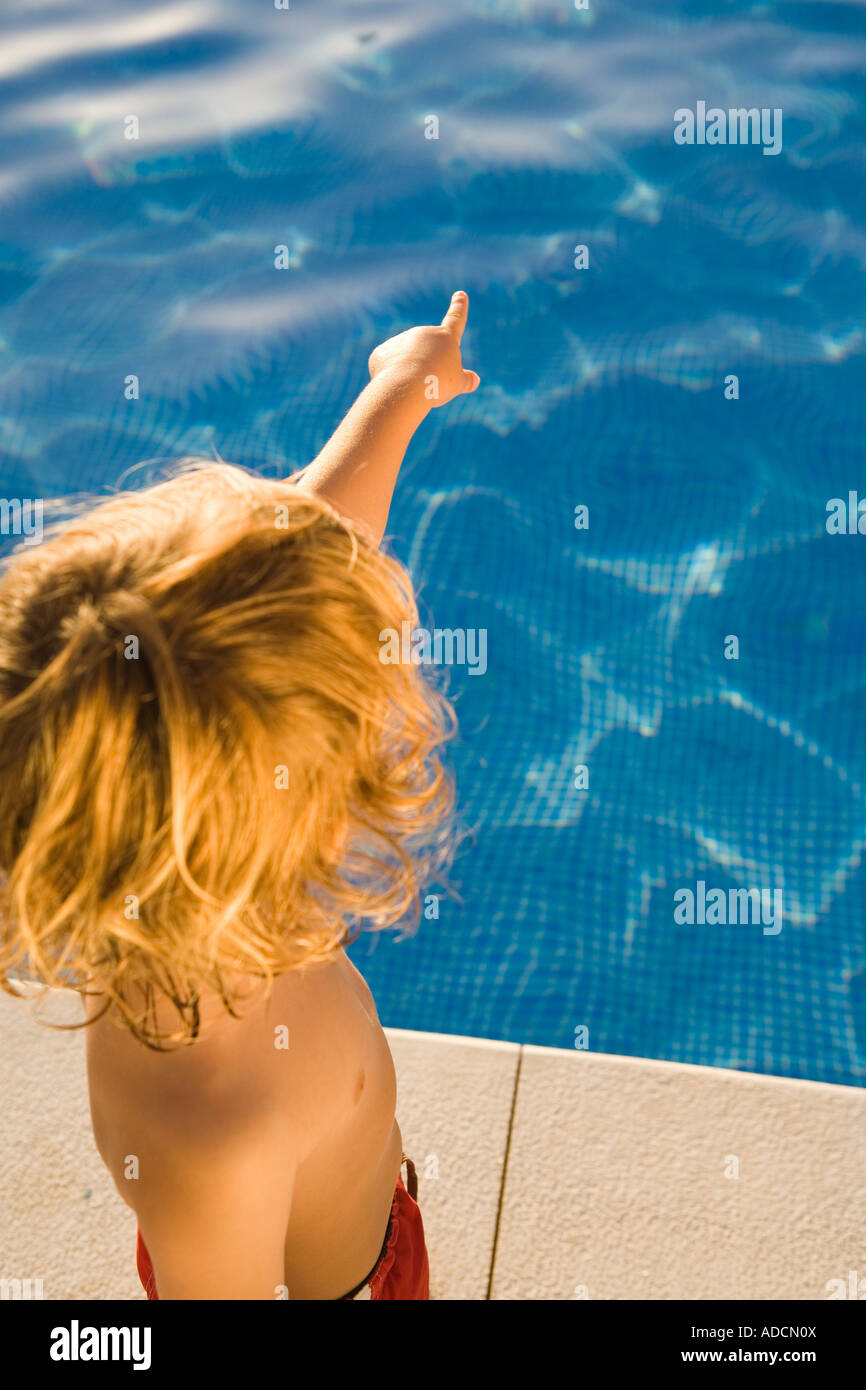 Jungen zeigen neben Schwimmbad Stockfoto