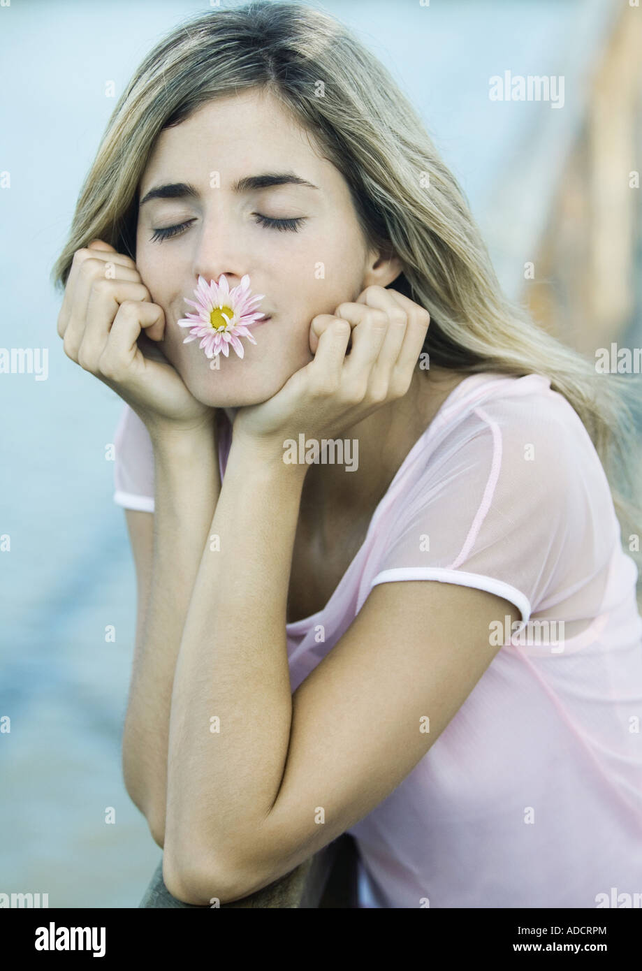 Frau mit Blume im Mund, Augen geschlossen Stockfoto