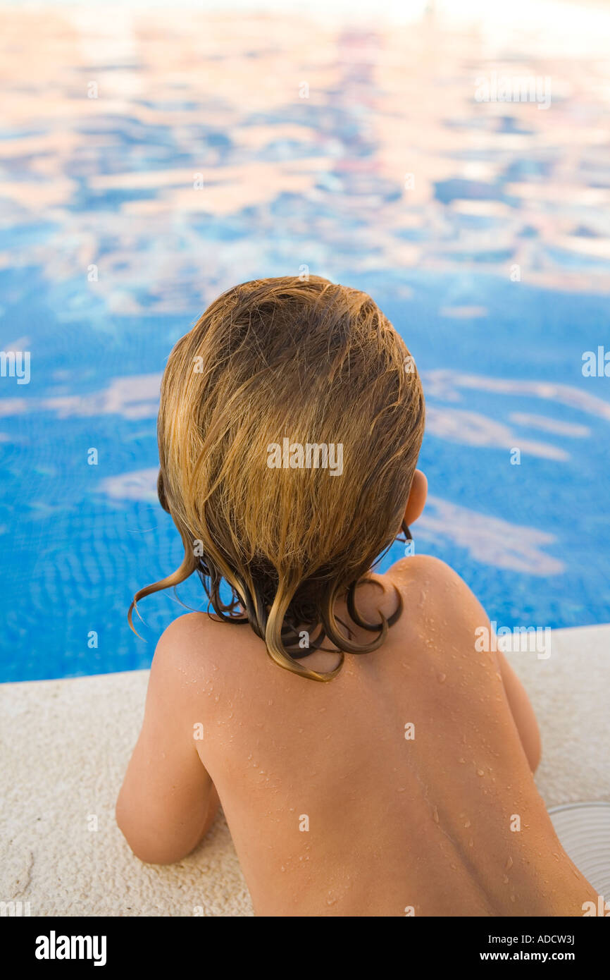 Kleiner Junge starrte auf das Wasser eines Schwimmbades, von hinten gesehen Stockfoto