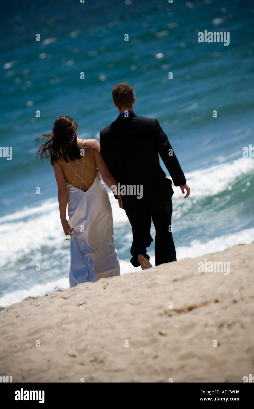 Frisch verheiratete Paar am Strand entlang in Richtung des Ozeans, die Hand in Hand Stockfoto