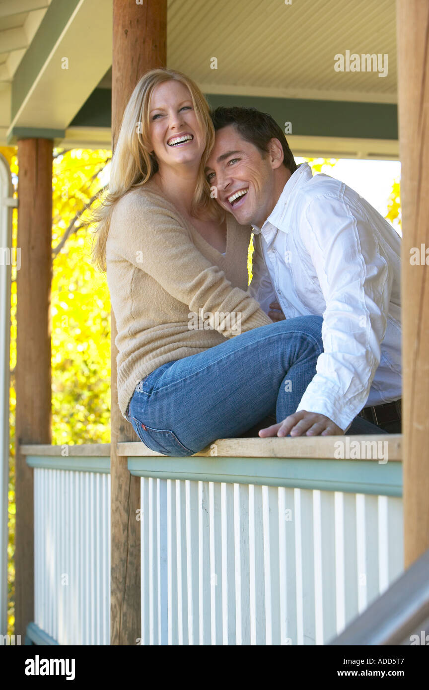 glückliche 30er Jahre sitzt Caucasian paar auf der Veranda Schiene lachend mit gelben Bäume im Herbst Stockfoto