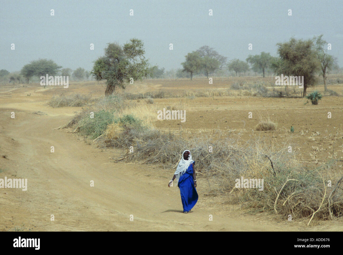 Verschleierte einheimische Frau allein zu Fuß auf einer staubigen Straße in Burkina Faso früher Obervolta Stockfoto