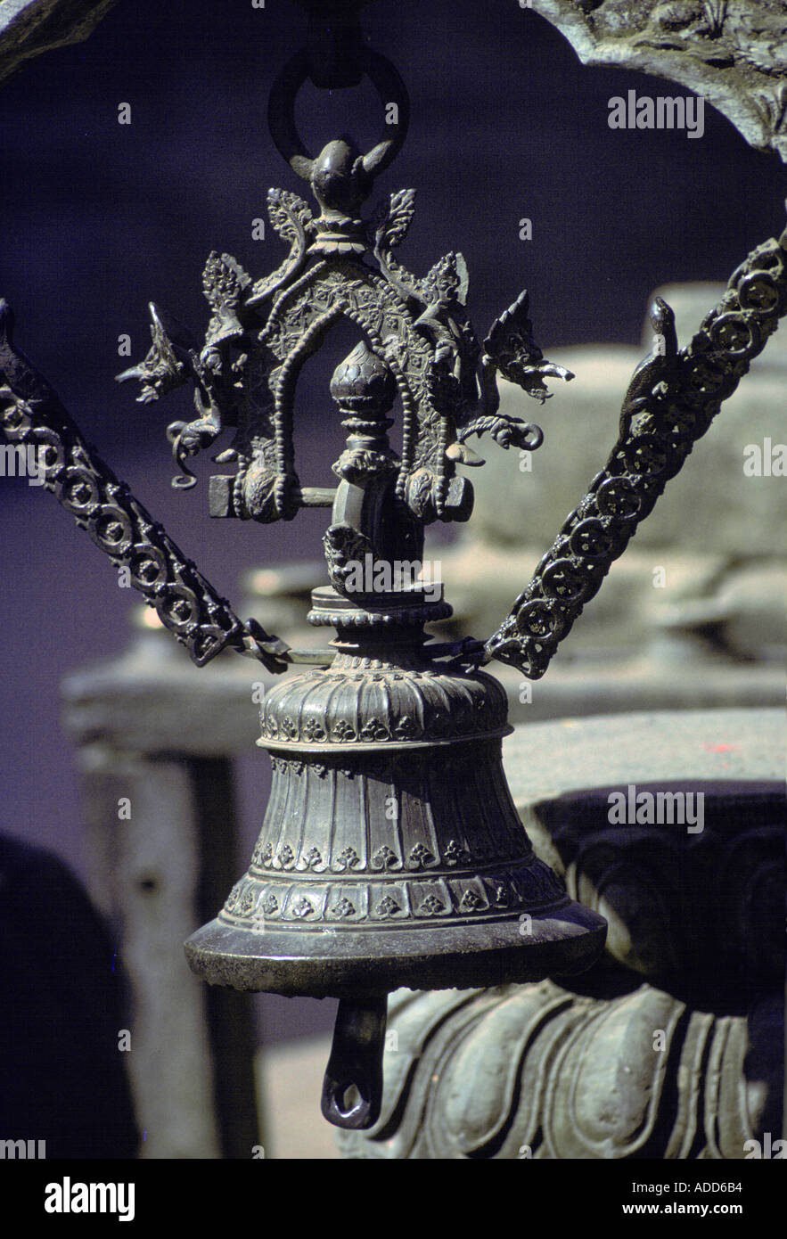 Metall Glocke verziert mit Drachen Kreaturen hängen von zwei Metallketten mit Eidechsen in Patan Nepal Stockfoto