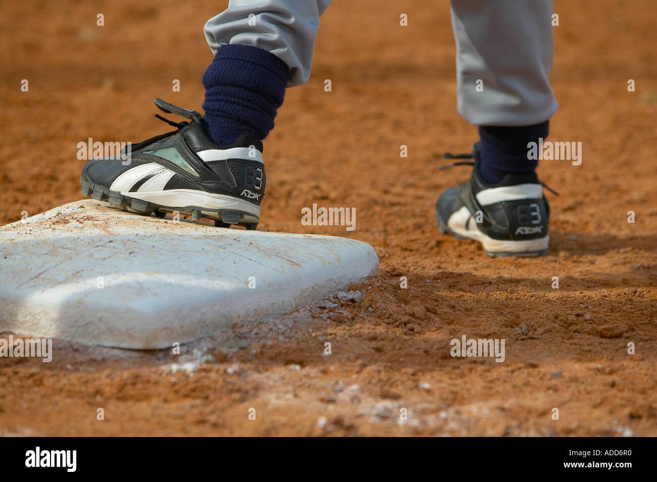 Kinder spielen Baseball mit einem Fuß auf der Basis Stockfoto