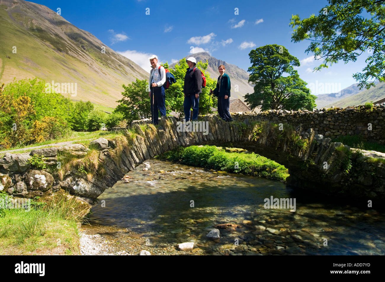 Familie über eine Stein-Bogen-Brücke über Mosedale Beck, Wasdale Head, in der Nähe von Wastwater, Lake District, Cumbria, England, UK Stockfoto