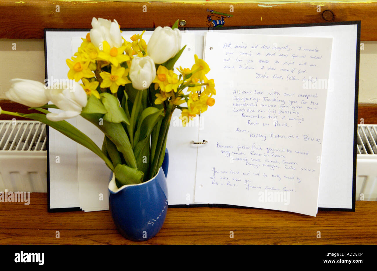 Blumen und Buch der Erinnerung in Erinnerung an Vater Paul Bennett erstochen auf dem Gelände seiner Kirche Wales UK Stockfoto