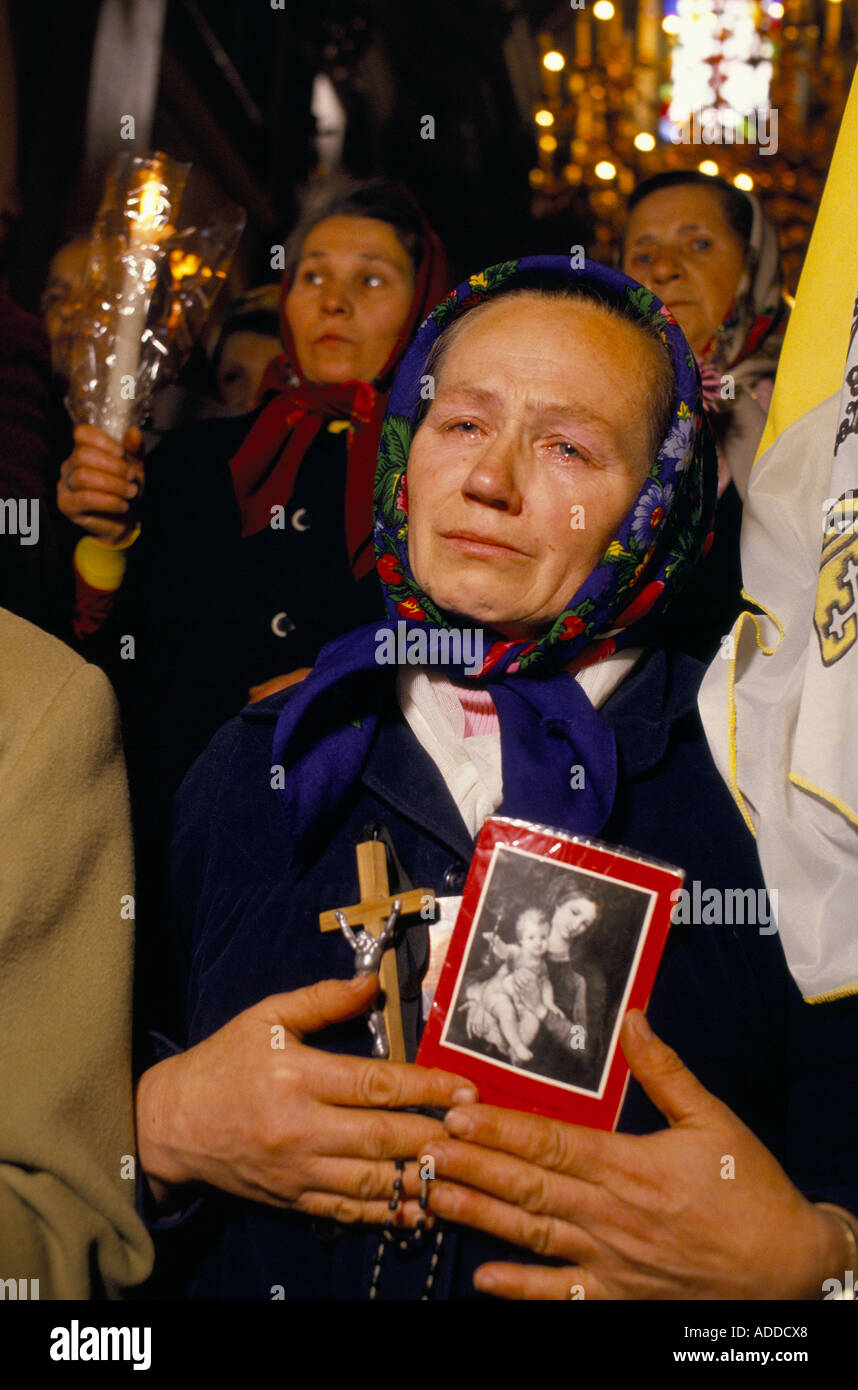 Ukraine, 1989; während des ersten katholischen Gottesdienstes in der Verklärung-Kirche in Lemberg seit 1946 weint eine Frau, die ein Kruzifix und Bilder von Maria Jesus trägt. Daneben ist eine päpstliche Fahne zu sehen.29. Oktober 1989 Stockfoto