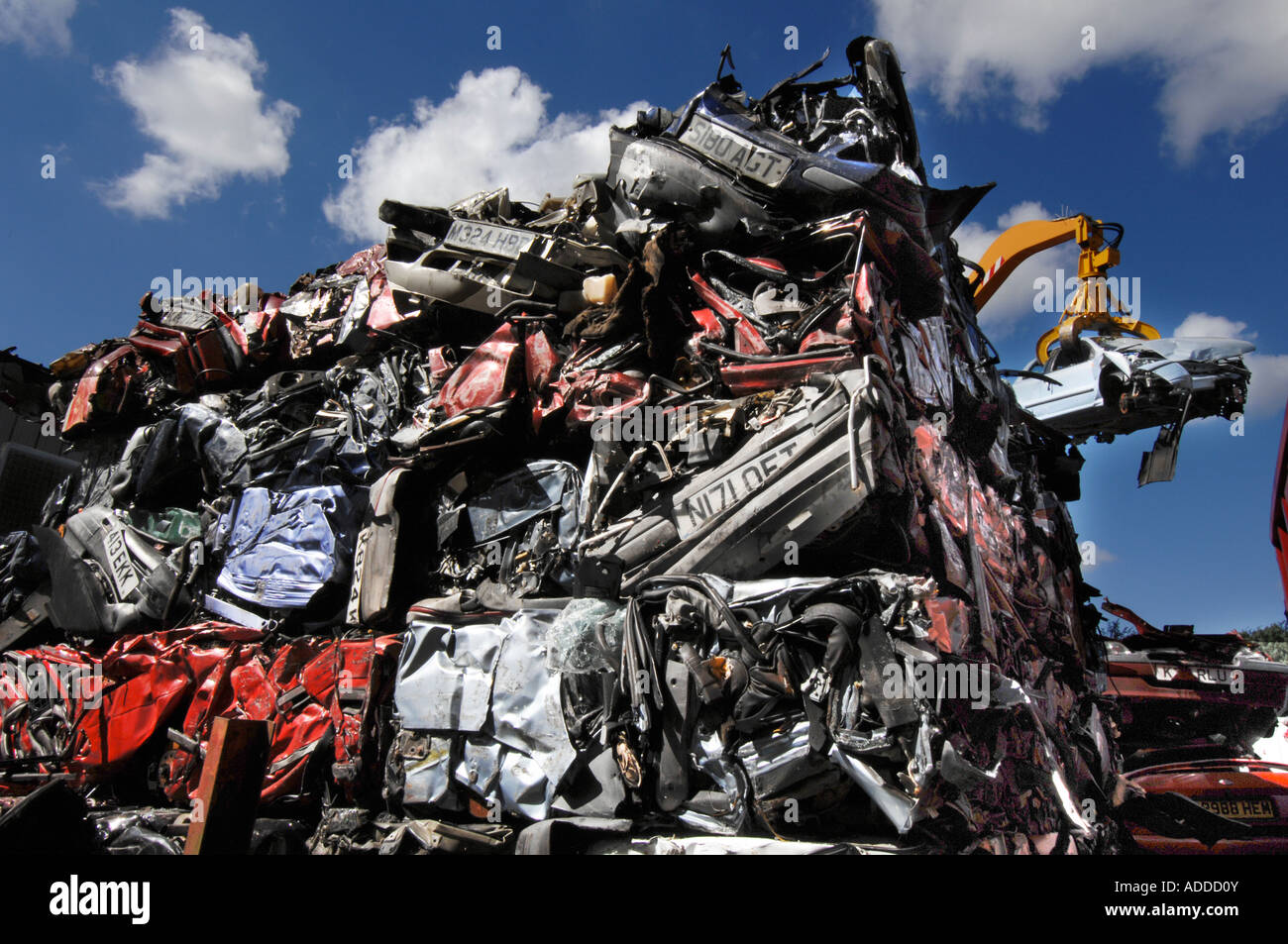 Würfel von zerquetschten Autos stehen in einen riesigen Haufen wie ein Kran ein Fiat Bravo in den Brecher hebt Stockfoto
