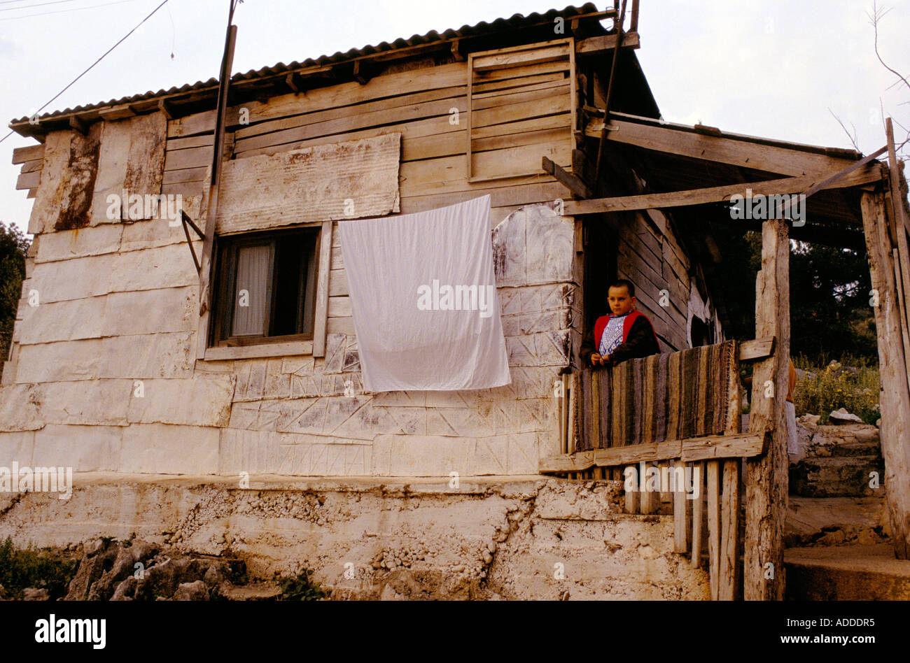 JUNGE STAND AUF DIE VERANDA DES HOLZES & BETON GEBÄUDE, EIN BEISPIEL FÜR SCHLECHTE WOHNVERHÄLTNISSE IN SARANDA, 1990 BEDINGUNGEN Stockfoto