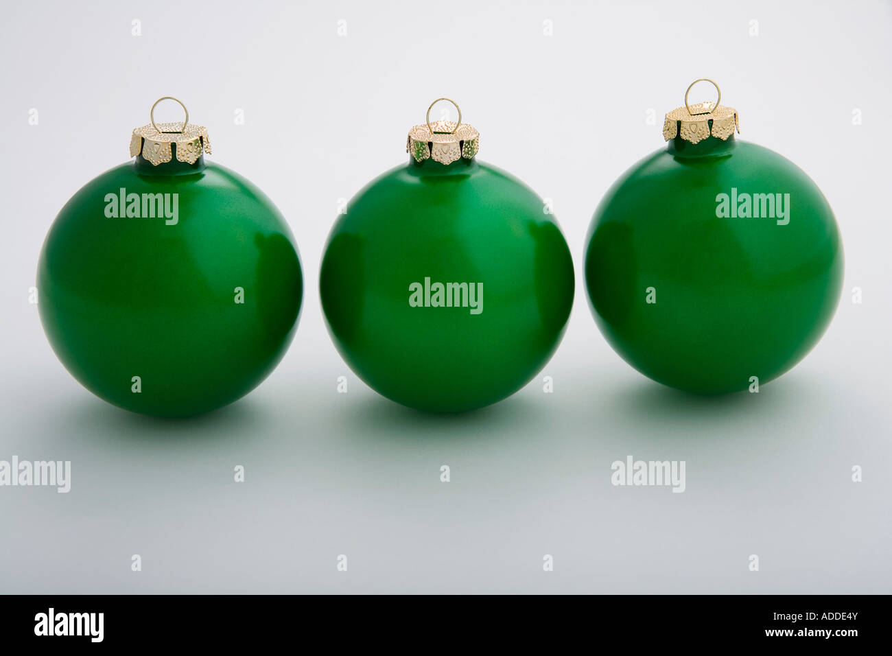 Drei grüne Weihnachtskugeln sitzen in einer Linie auf einem weißen Hintergrund Studioportrait Stockfoto