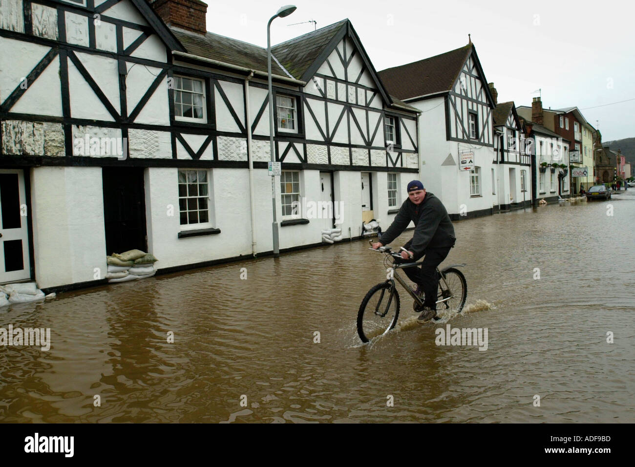 Überschwemmungen in Monmouth, nach dem Fluss Monnow seine Banken Monmouthshire South Wales UK Mann auf Fahrrad platzen Stockfoto