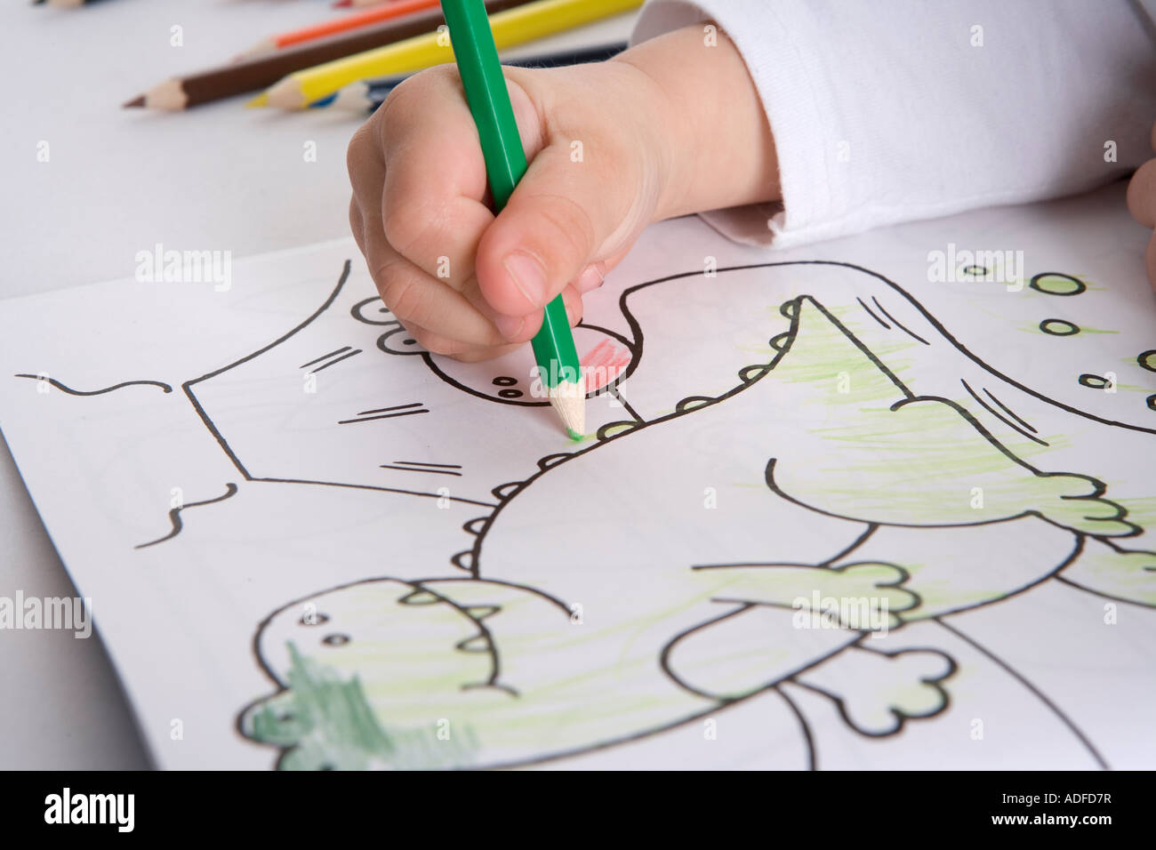 Nahaufnahme von einer Kinderhand Färbung eines Dinosauriers Stockfoto