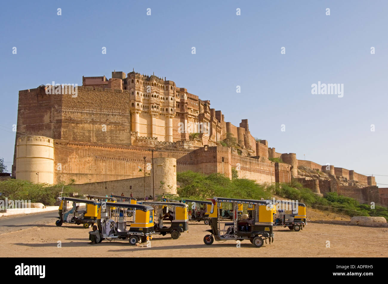 Eine Weitwinkelaufnahme des Mehrangarh Forts vor blauem Himmel mit Auto-Rikschas im Vordergrund warten auf Touristen zu nehmen. Stockfoto