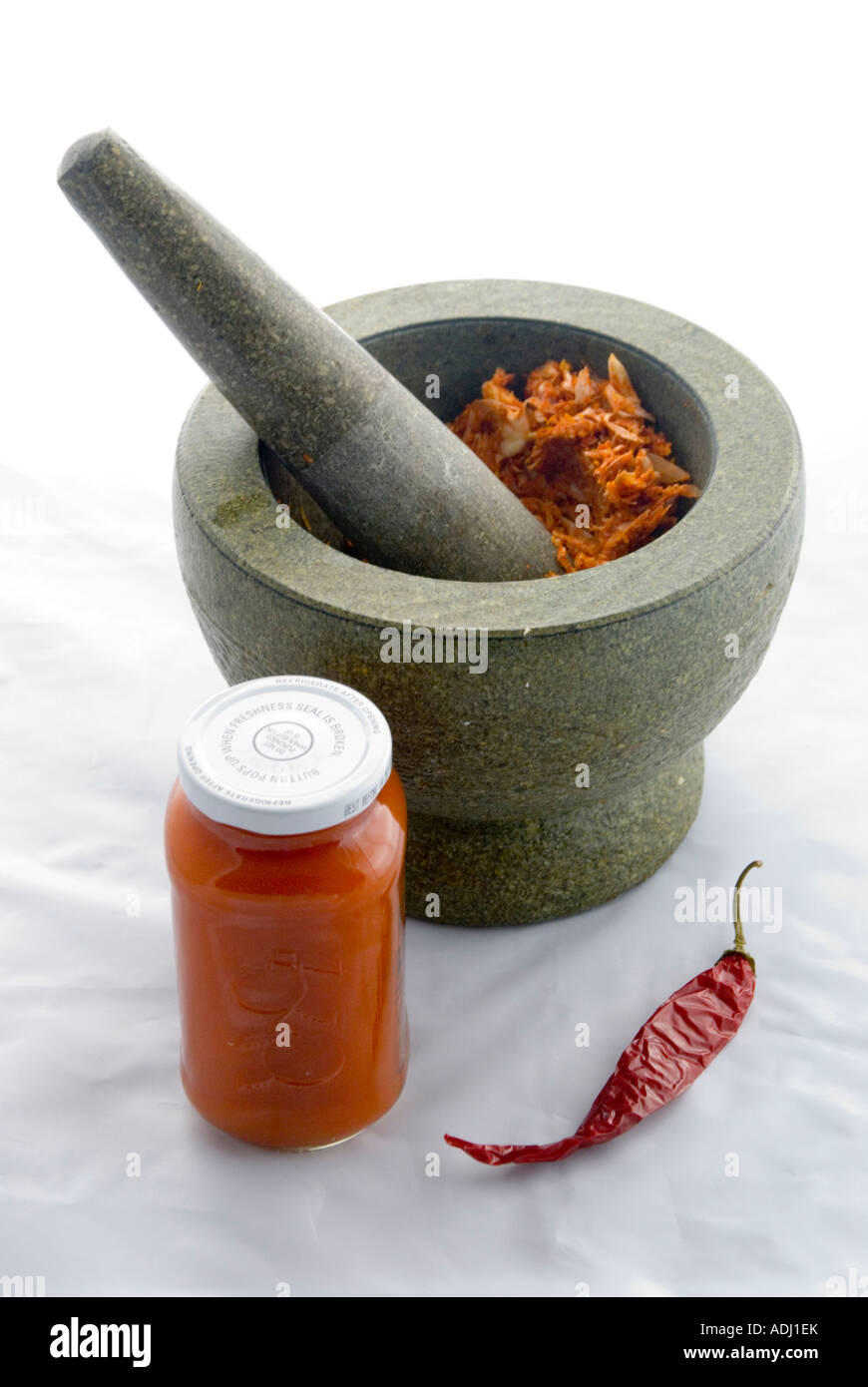 Eine hausgemachte scharfe Knoblauch-Chili-Paste, die in einem traditionellen schweren chinesischen Stößel und Mörser gehackt wird Stockfoto
