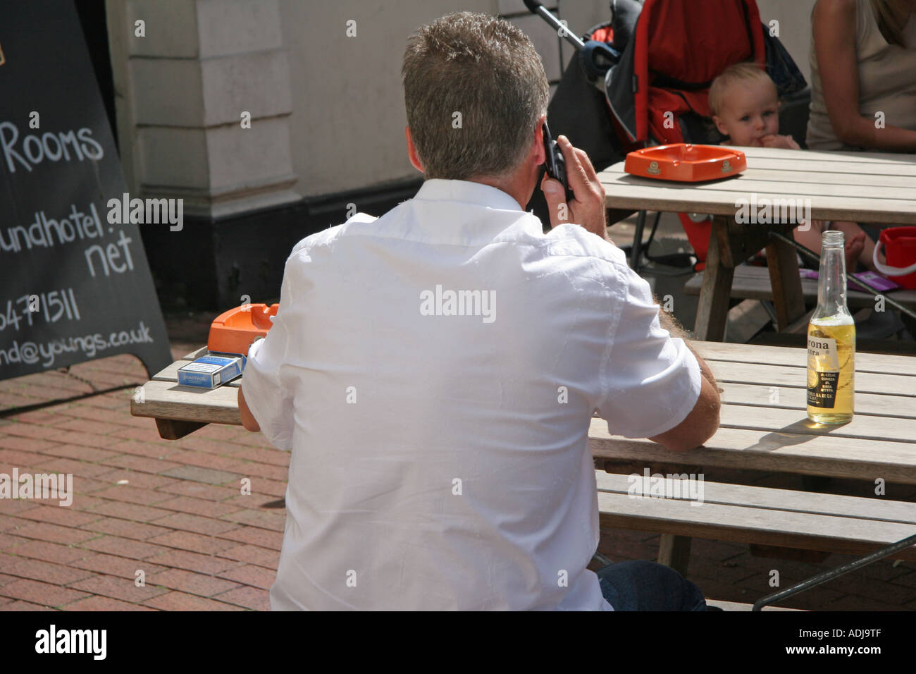 Mann spricht auf Handy im Gastgarten Stockfoto