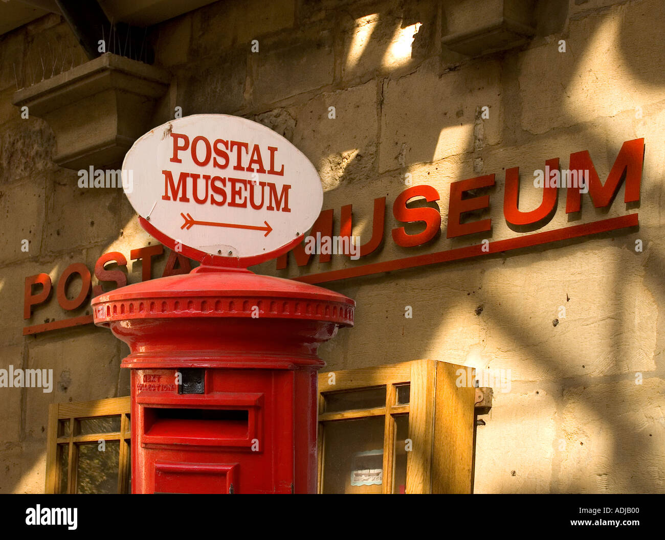 Rote Säule Box mit Zeichen für die National Postal Museum, außen hinter der frühere Museum Adresse bei 8 Broad Street, Badewanne, Avon, Großbritannien Stockfoto