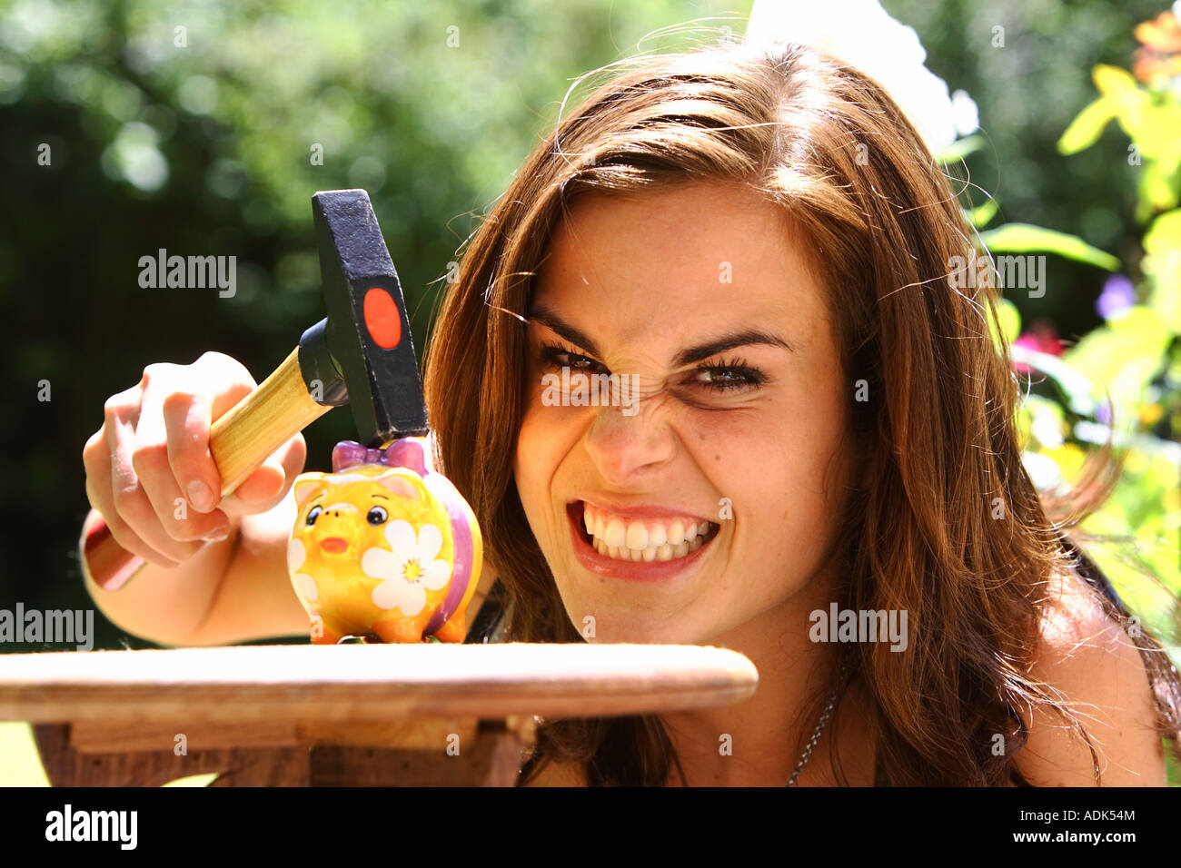 Junge Frau raubt ein Sparschwein mit einem Hammer © Peter Schatz/Alamy Stockfoto