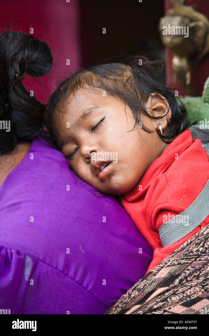 Einheimische Frau sitzen beim tragen ein kleines Mädchen auf dem Rücken in die Stadt Bhaktapur in der Nähe von Kathmandu-Nepal Stockfoto