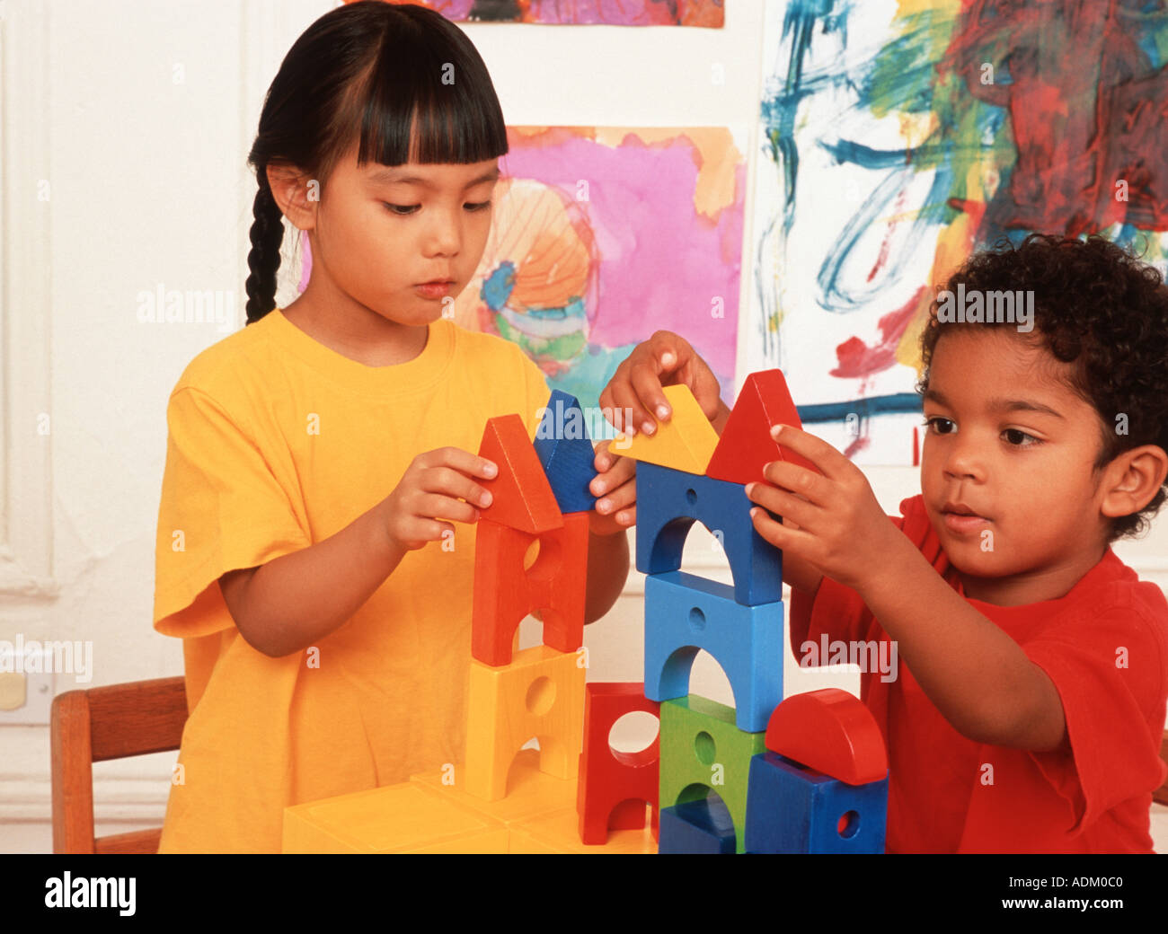 4 Jahre alter Junge und 4 jährige Mädchen gemeinsam mit Blöcken bauen, asiatische vietnamesische und biracial African American Hispanic Stockfoto