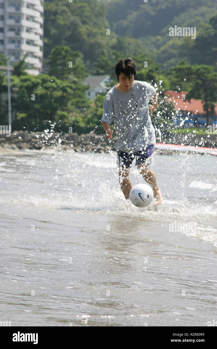 Junger Mann spielen Fußball am Strand Stockfoto