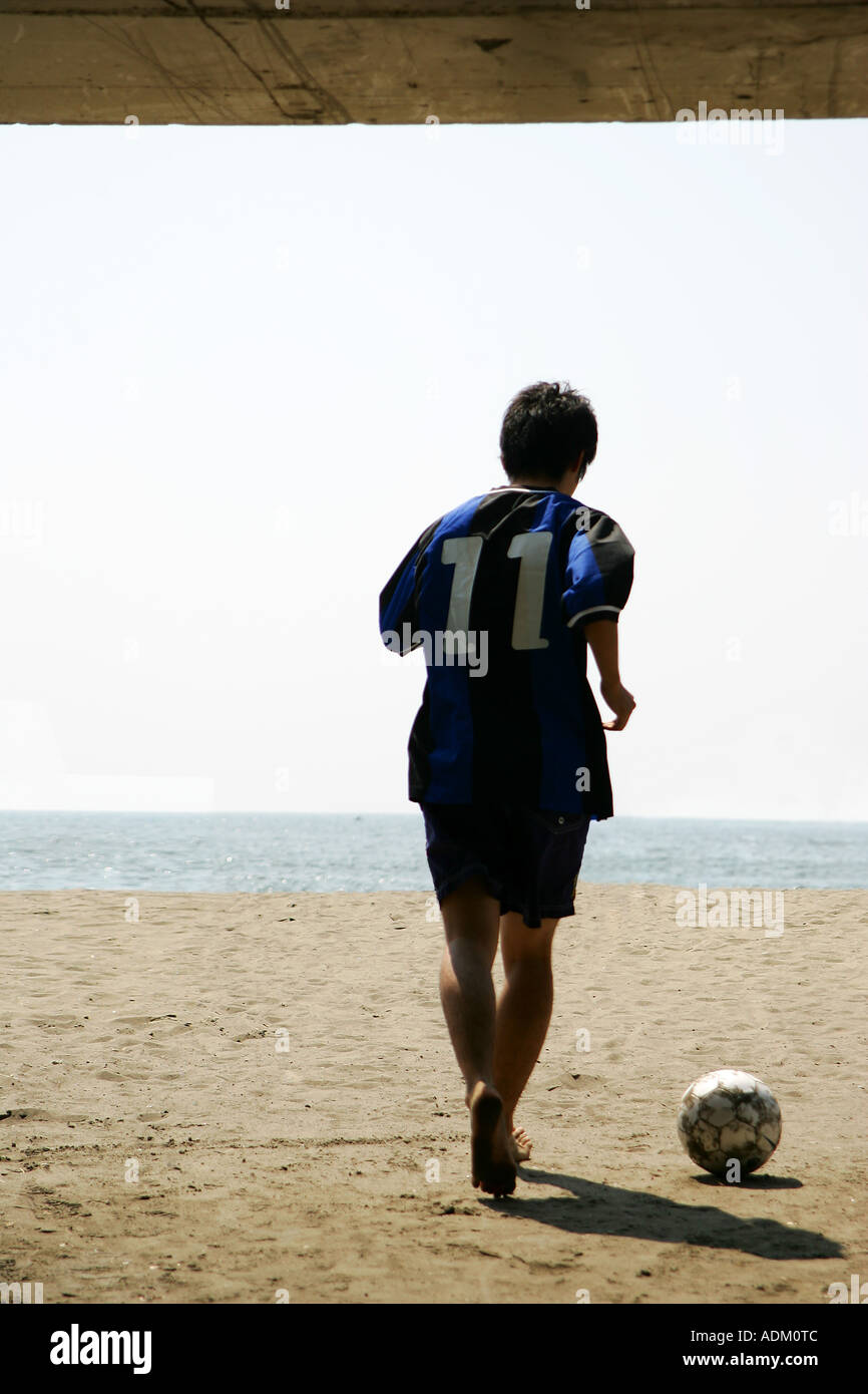 Silhouette eines jungen Mannes mit einem Fußball am Strand Stockfoto