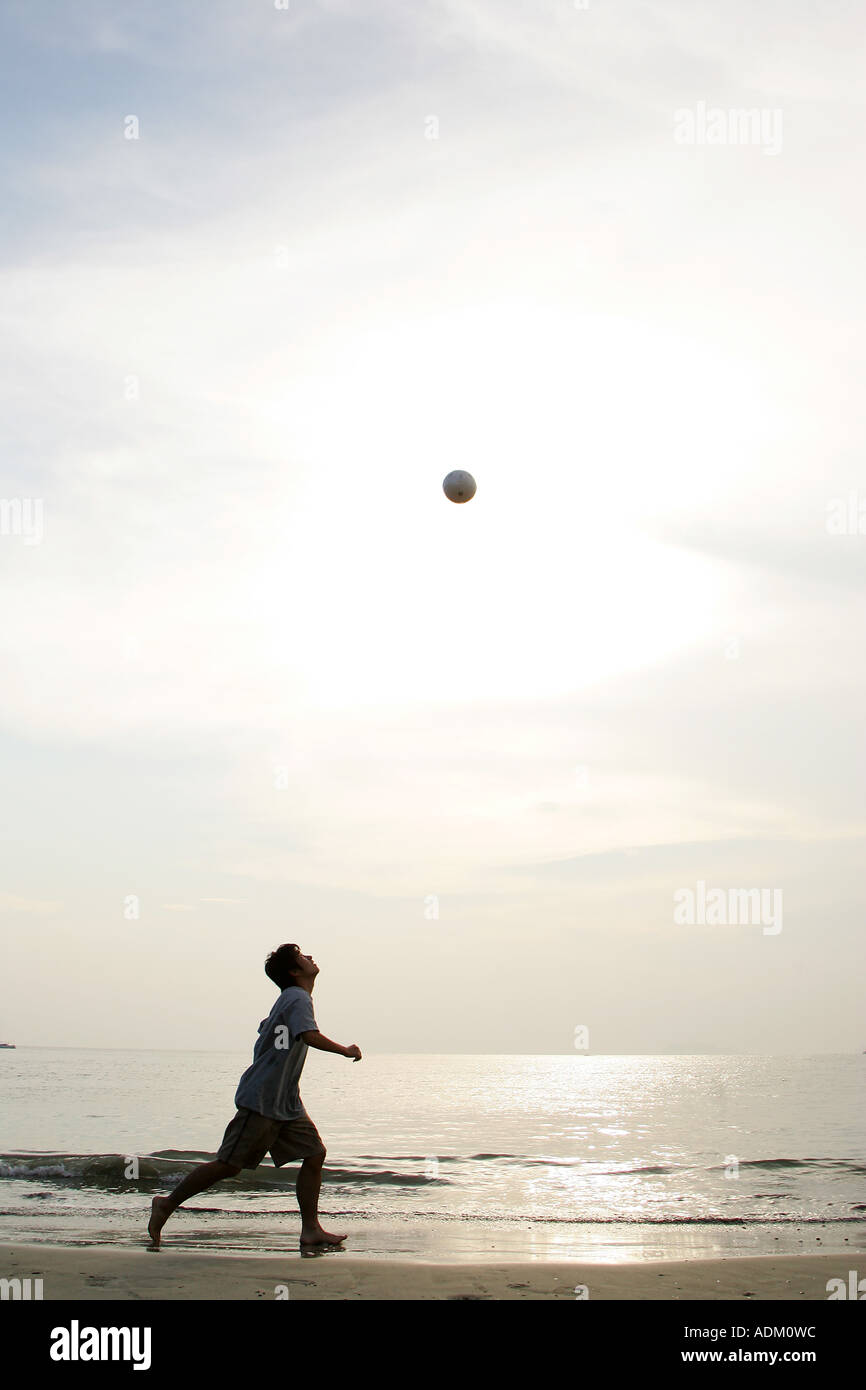 Junger Mann spielen Fußball am Strand Stockfoto