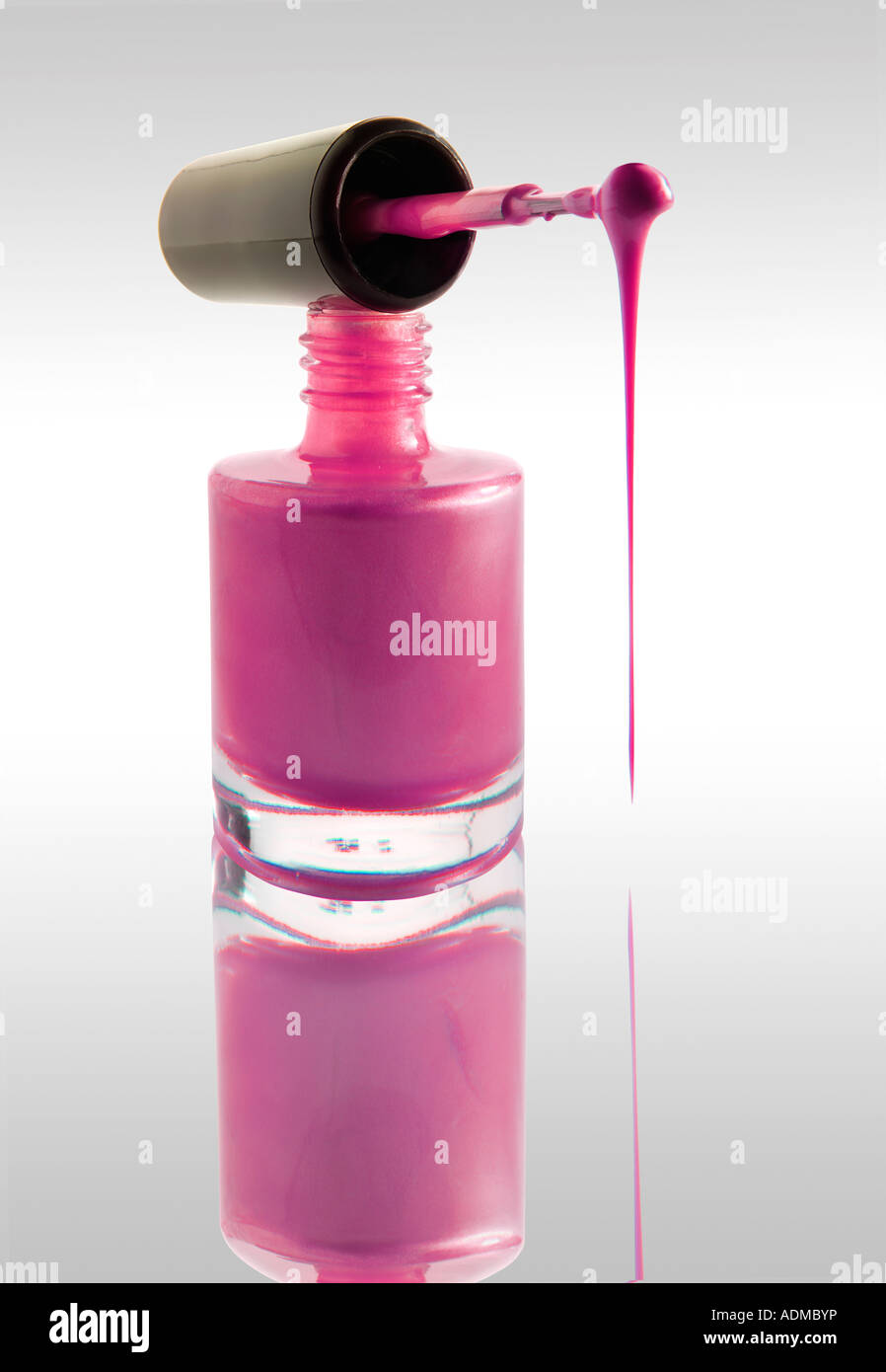 Nagellack tropft aus einem Nagel Lack Pinsel balancierte auf einem Nagel Lack Flasche rosa Farbe gegen weiß mit einer Reflexion Stockfoto