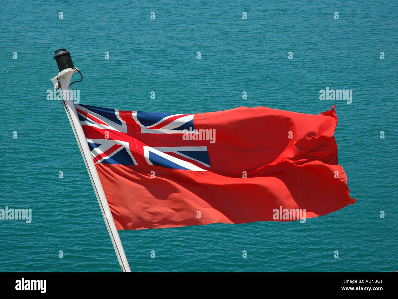 Red Ensign Fahne von einem UK-Schiff gegen das blaue Meer Stockfoto