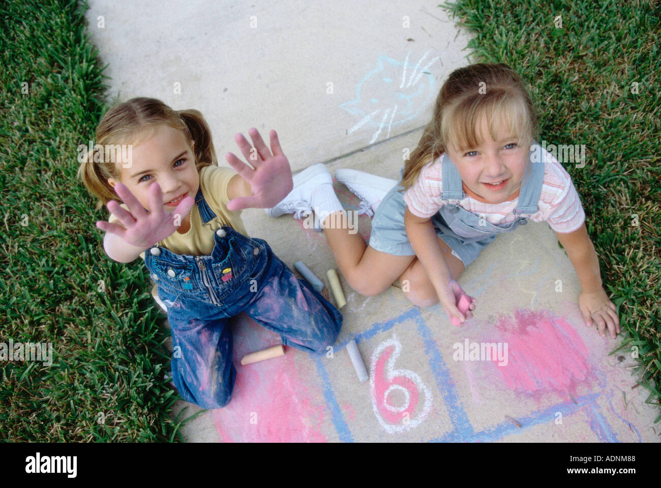 Porträt von zwei Mädchen auf dem Boden mit Kreide Stockfoto