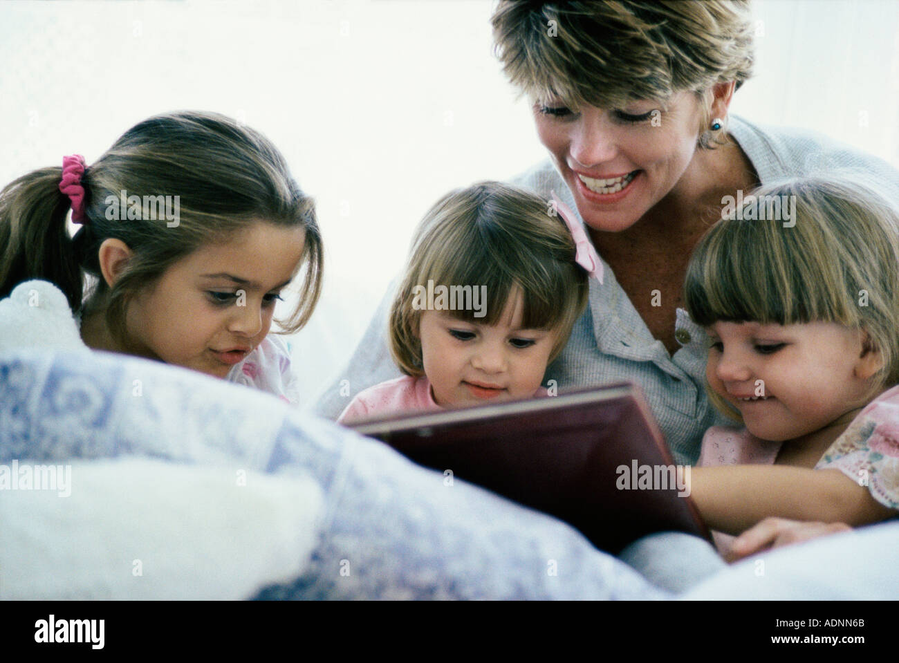 Mutter mit ihren drei Töchtern ein Buch zu lesen Stockfoto