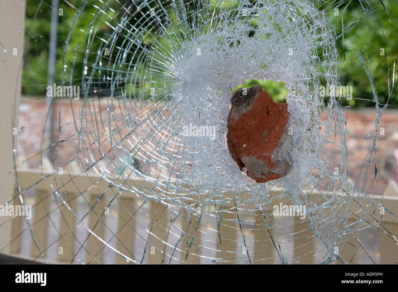 Old Red Brick in gebrochenem klemmt vorgespanntem Glas Fenster geworfen durch Vandalen in ein Haßverbrechen in im Haus Stockfoto