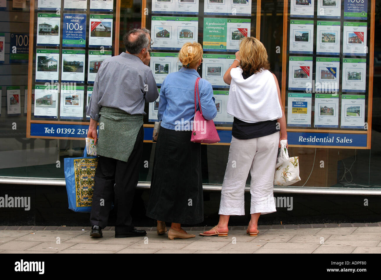 Ein Mann und zwei Frauen, die in das Fenster ein Immobilienmakler in Exeter, Devon, UK Stockfoto
