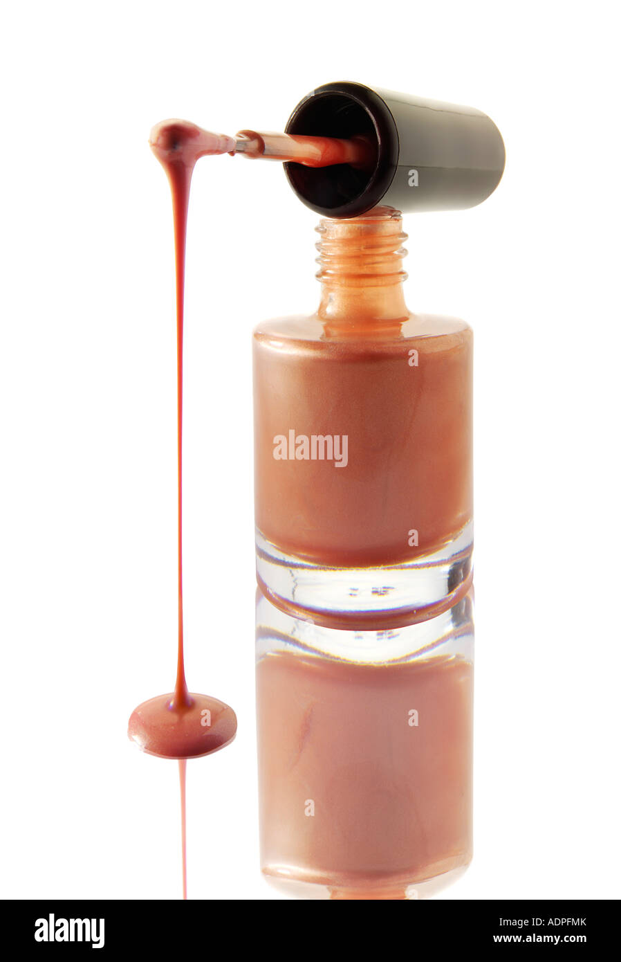 Nagellack tropft aus einem Nagel Lack Pinsel balancierte auf einem Nagel Lack Flasche Pfirsich Farbe gegen weiß mit einer Reflexion Stockfoto