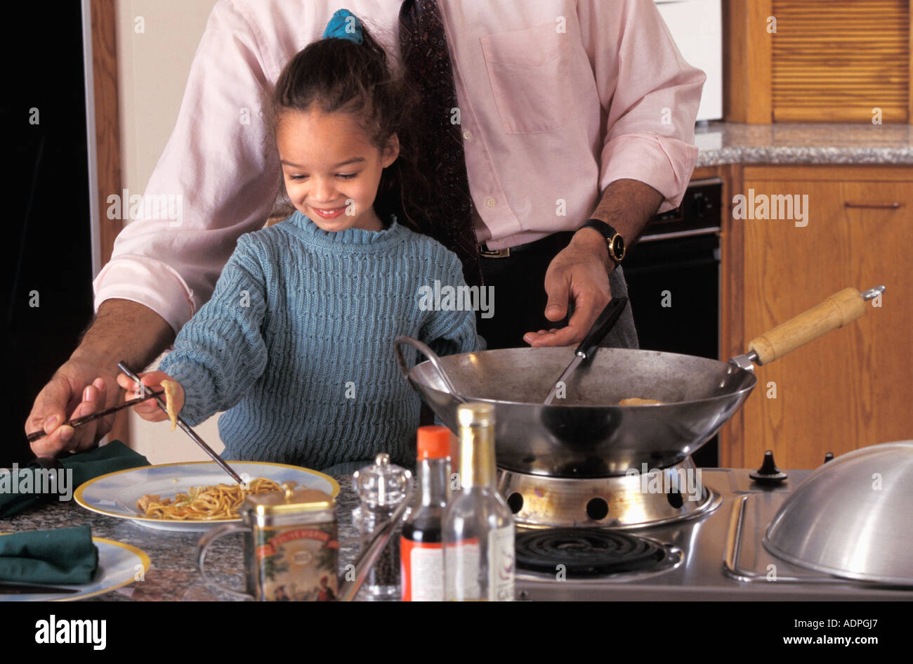 Latino-Vater und Tochter Vorbereitung unter Rühren braten in Küche Stockfoto