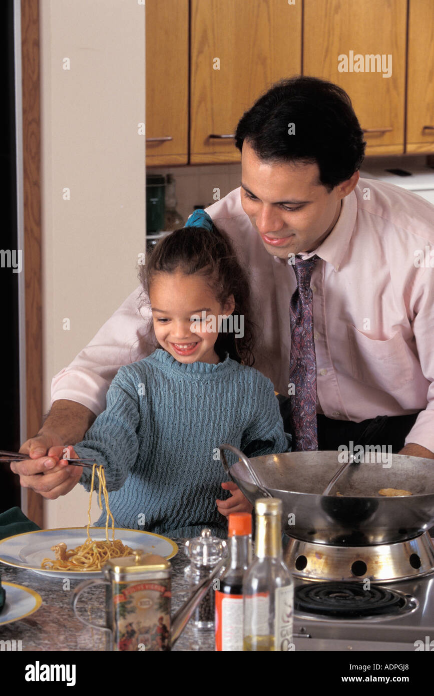 Latino-Vater und Tochter Vorbereitung unter Rühren braten in Küche Stockfoto