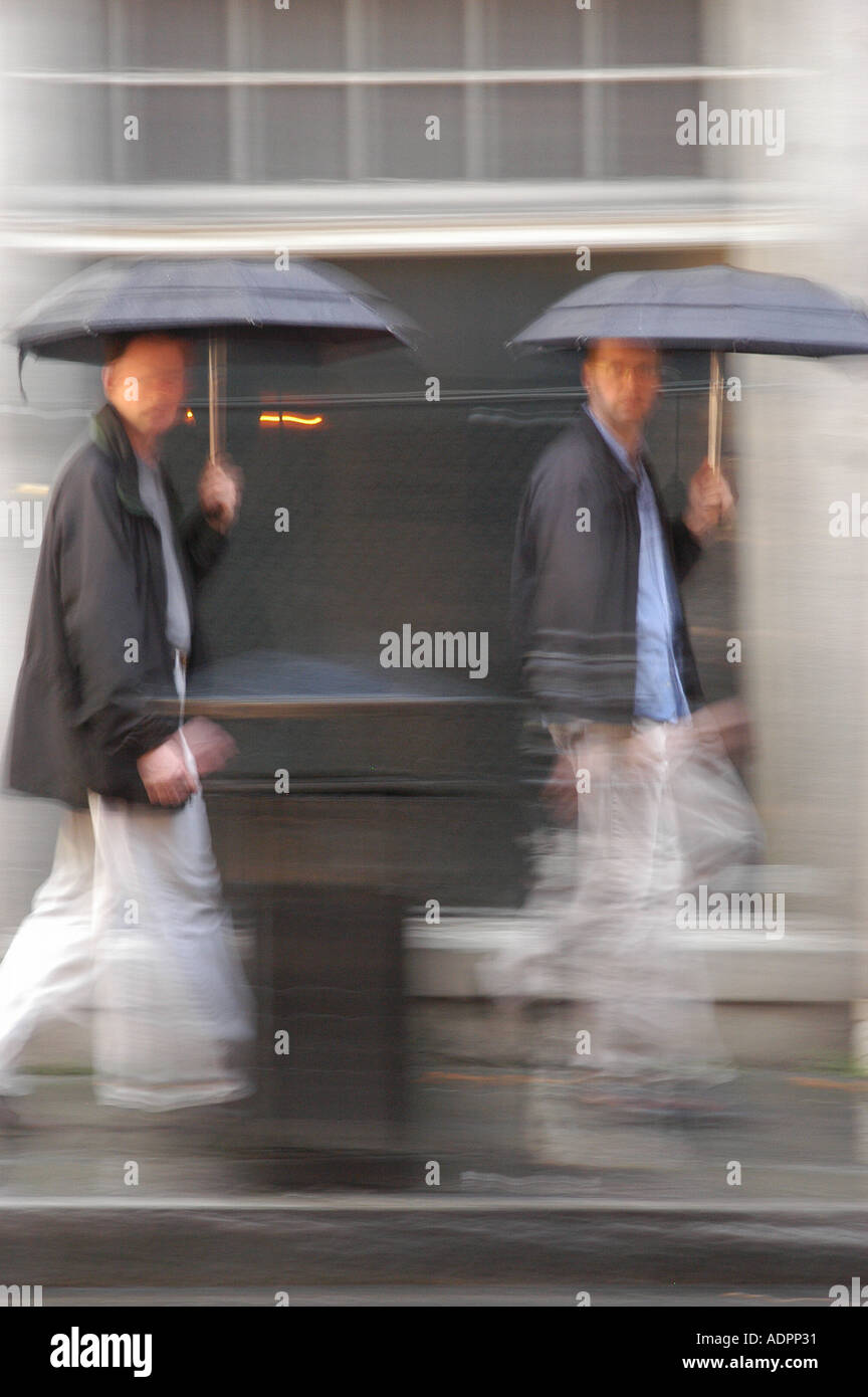 Zwei Männer mit Sonnenschirmen zu Fuß auf dem Bürgersteig im French Quarter New Orleans Louisiana Stockfoto