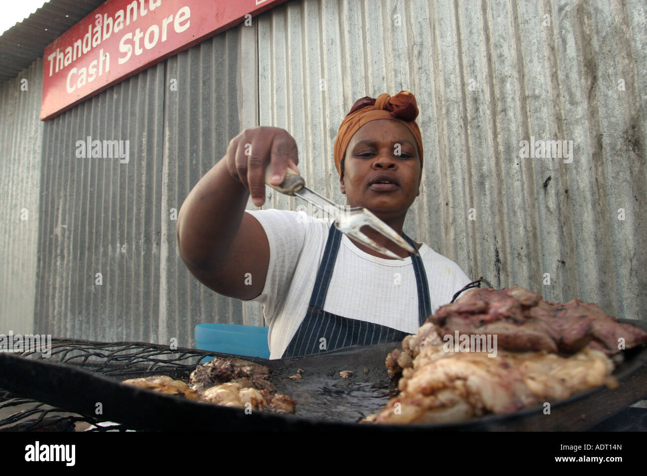 Frau fries Schafe Leber über Kohlen auf dem Bürgersteig außerhalb einer Gemeinde shop, Phillipi, in der Nähe von Khayelitsha, Kapstadt. Stockfoto