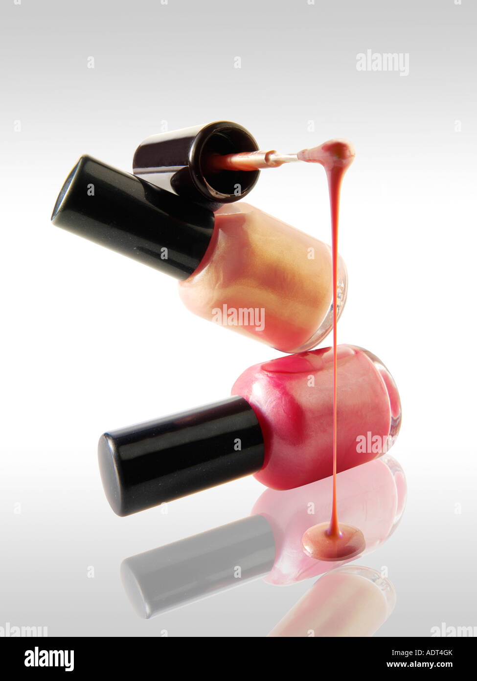Nagellack tropft aus einem Nagel Lack Pinsel balancierte auf einem Nagel Lack Flasche rosa Farbe gegen weiß mit einer Reflexion Stockfoto