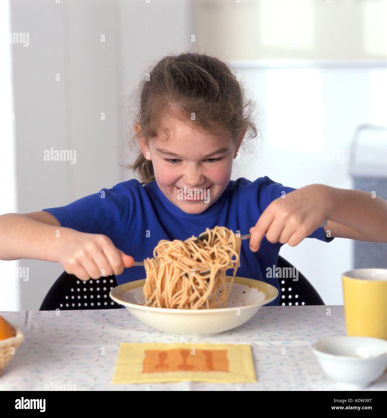 Mädchen, die Pasta mit Löffel und Gabel zu essen Stockfoto