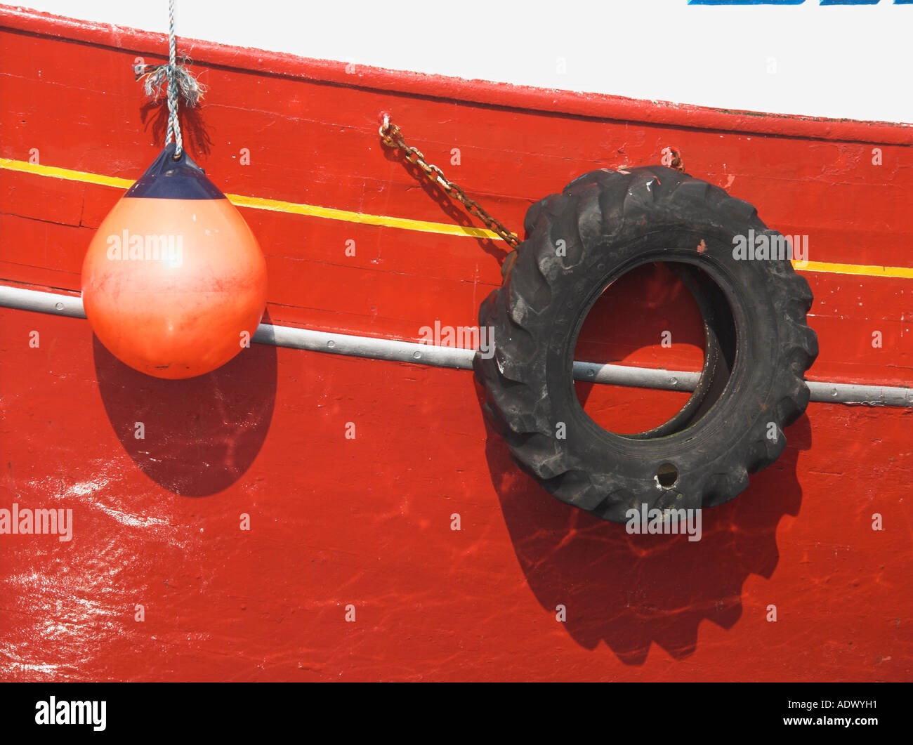 Bouy und alten Reifen hängen neben den Rumpf eines rot Fischerbootes Stockfoto