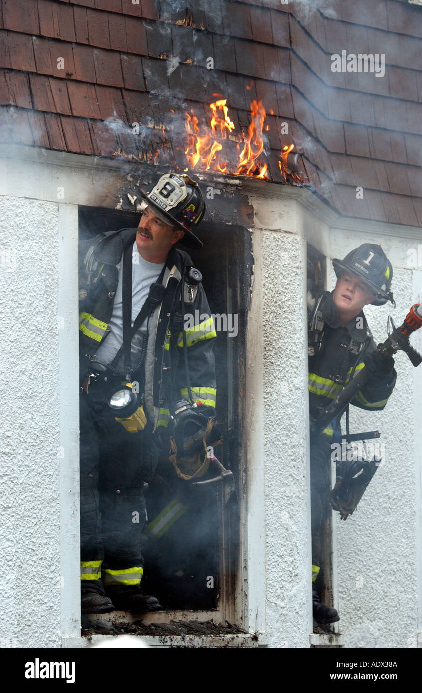 Feuerwehr Feuerwehr auf der Suche nach einem Brand, wie es über ihnen in einem Haus brennt Feuer Notfall Stockfoto