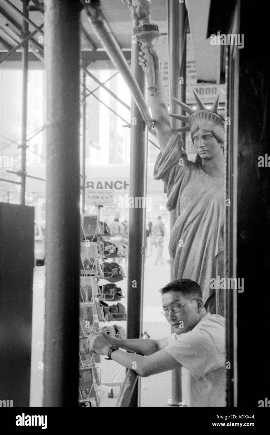 Mann sitzt neben Replik der Statue of Liberty, New York City Stockfoto
