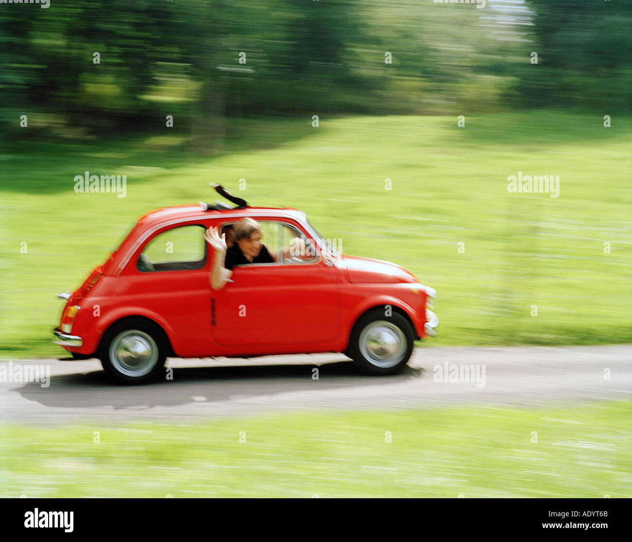 rote italienische Kleinwagen mit einem Mann Waiwing vom Beifahrersitz Stockfoto