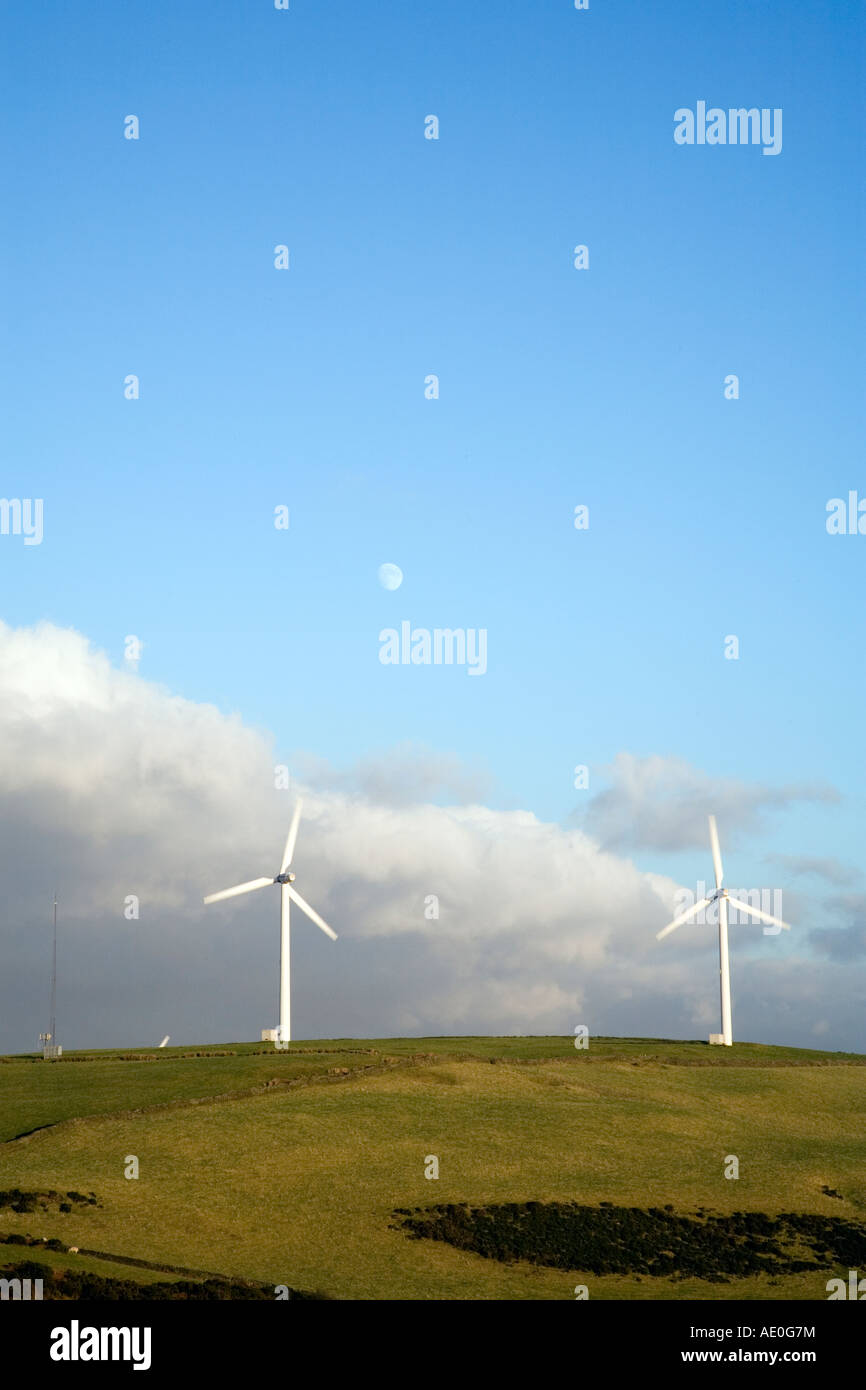 Ländlicher Hang mit zwei Windturbinen vor blauem Himmel Mit etwas Wolke und dem Mond Stockfoto