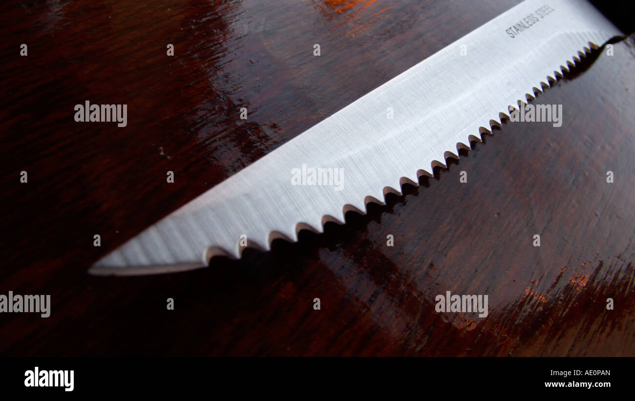 Messer aus rostfreiem Stahl auf einem lackierten Holztisch Stockfoto