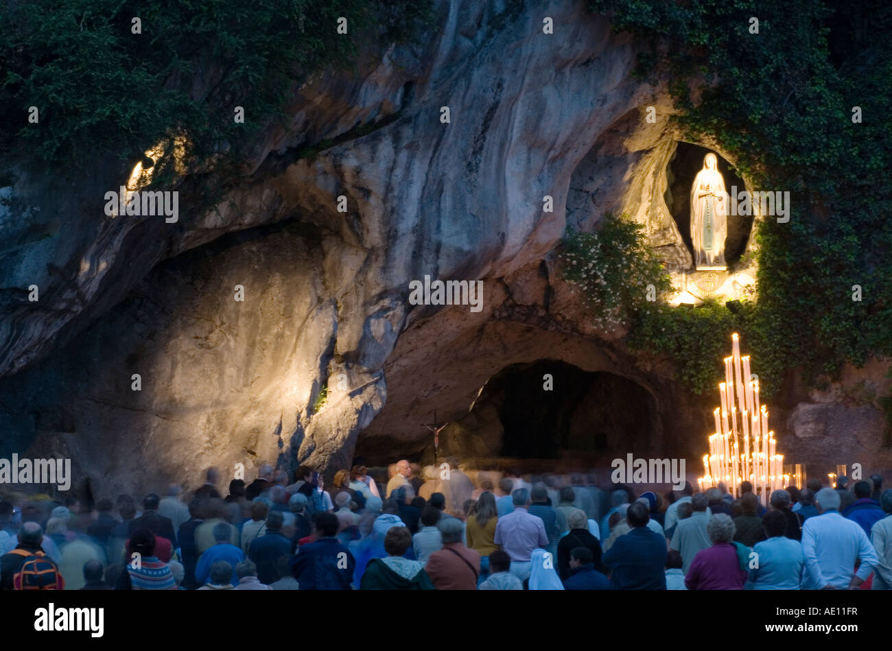 Pilger beten an der Grotte von Massabielle in Lourdes am Abend, Frankreich Stockfoto