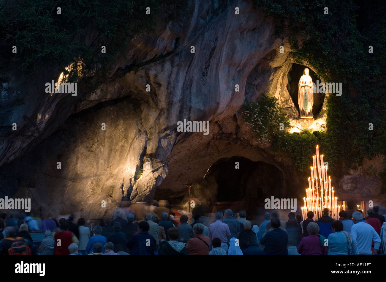 Pilger beten an der Grotte von Massabielle in Lourdes am Abend, Frankreich Stockfoto